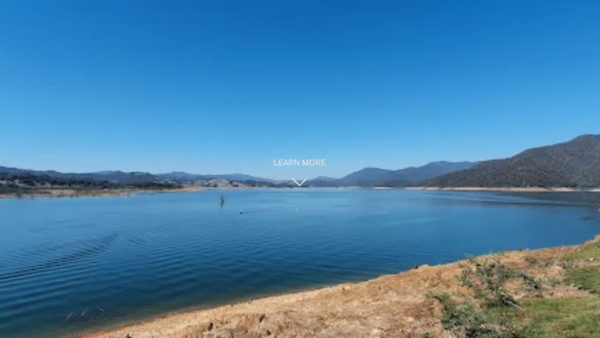 alm lake with rocky shore, surrounding hills, and clear blue sky