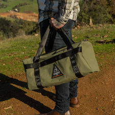 Person holding a green bag with a logo in a natural setting