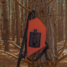 Orange hunting radio holster attached to a tree in a forest