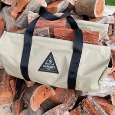 Beige wood carrier with black straps holding logs of food on a pile of firewood