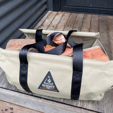 Beige carrying bag with black straps holding firewood, branded 'Summit', on a wooden step.