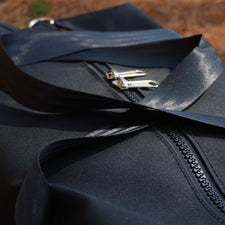 black canvas bag on pinecone covered gound