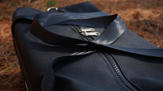 black canvas bag on pinecone covered gound