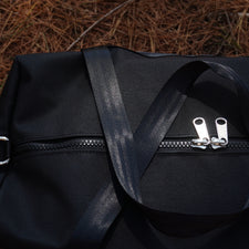 black canvas bag on pinecone covered gound