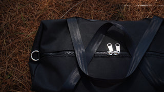 black canvas bag on pinecone covered gound