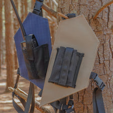 Blue and Sand Radio Holsters attached to a tree in a forest setting