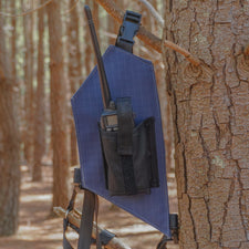 Blue radio holster attached to a tree in a forest setting