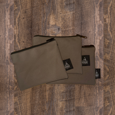 Three brown canvas pencil cases with a zipper closure, placed on a wooden surface.