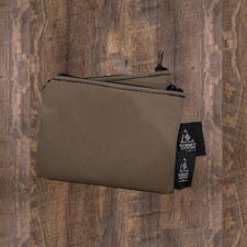 Two brown canvas pencil cases with a zipper closure, placed on a wooden surface.