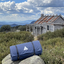 Canvas bag on rock with cabin and mountain landscape in background