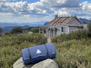 Canvas bag on rock with cabin and mountain landscape in background
