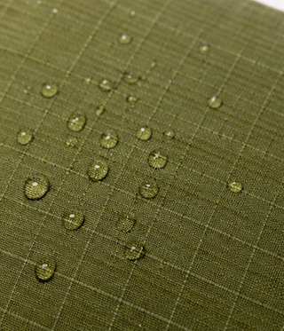 Green fabric with water droplets demonstrating water resistance.