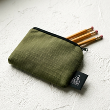 Green pencil case with pencils on a white surface