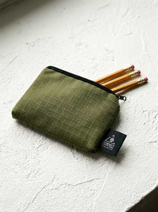 Green pencil case with pencils on a white surface