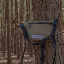Beige radio holster attached to a tree in a forest setting