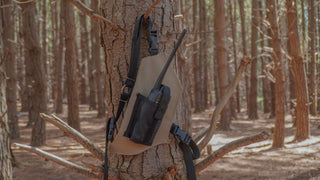 Beige radio holster attached to a tree in a forest setting
